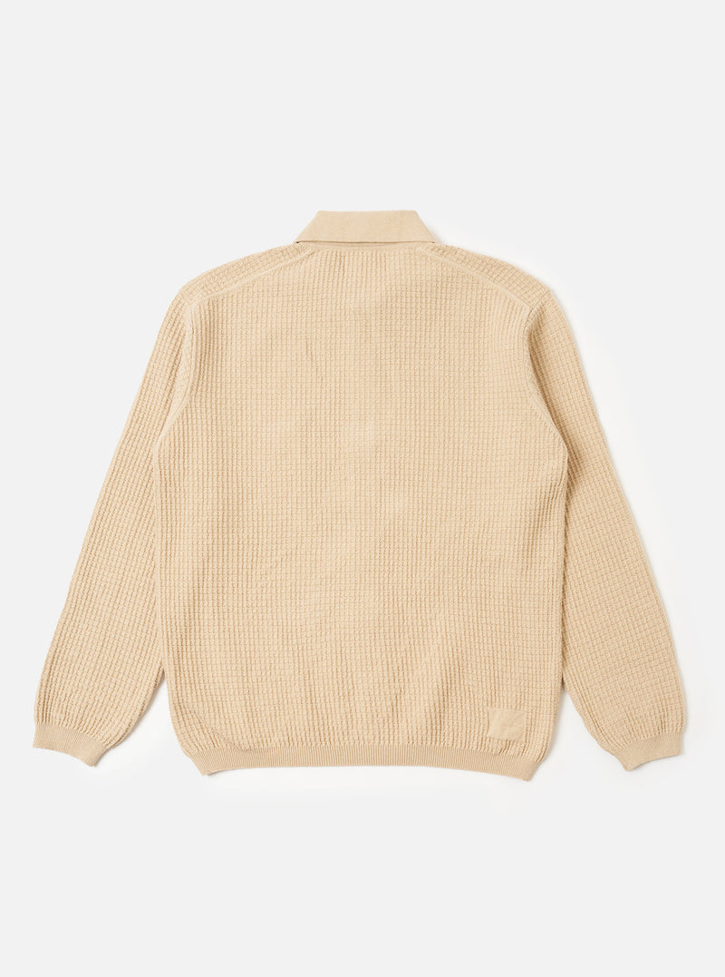 The Sand Eco Cotton Knit Jacket is shown from a rear angle as a flat lay against a white background. The jacket features long sleeves, a straight hem, and ribbed detailing at the cuffs and hem. The knitted fabric has a textured appearance.