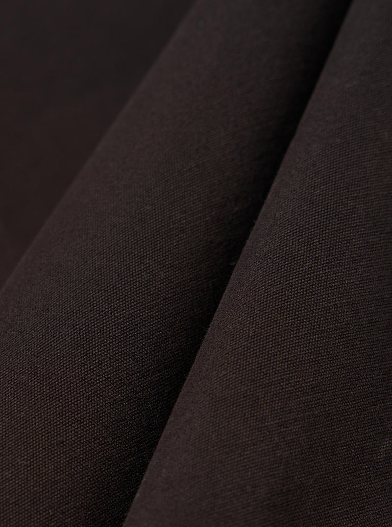 A close-up fabric swatch of the Licorice Summer Canvas Labour Jacket highlights a deep brown color and a durable, woven canvas texture. The image shows the material as a solid, flat surface with a subtle, suede-like finish.