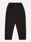 The Licorice Summer Canvas Pleated Track Pant is shown as a flat lay against a plain white background. The trousers feature an elasticated waistband with an internal drawstring, a single pleat on each leg, and a tapered silhouette. The fabric is a solid licorice brown cotton canvas with visible stitching at the hem and pockets.