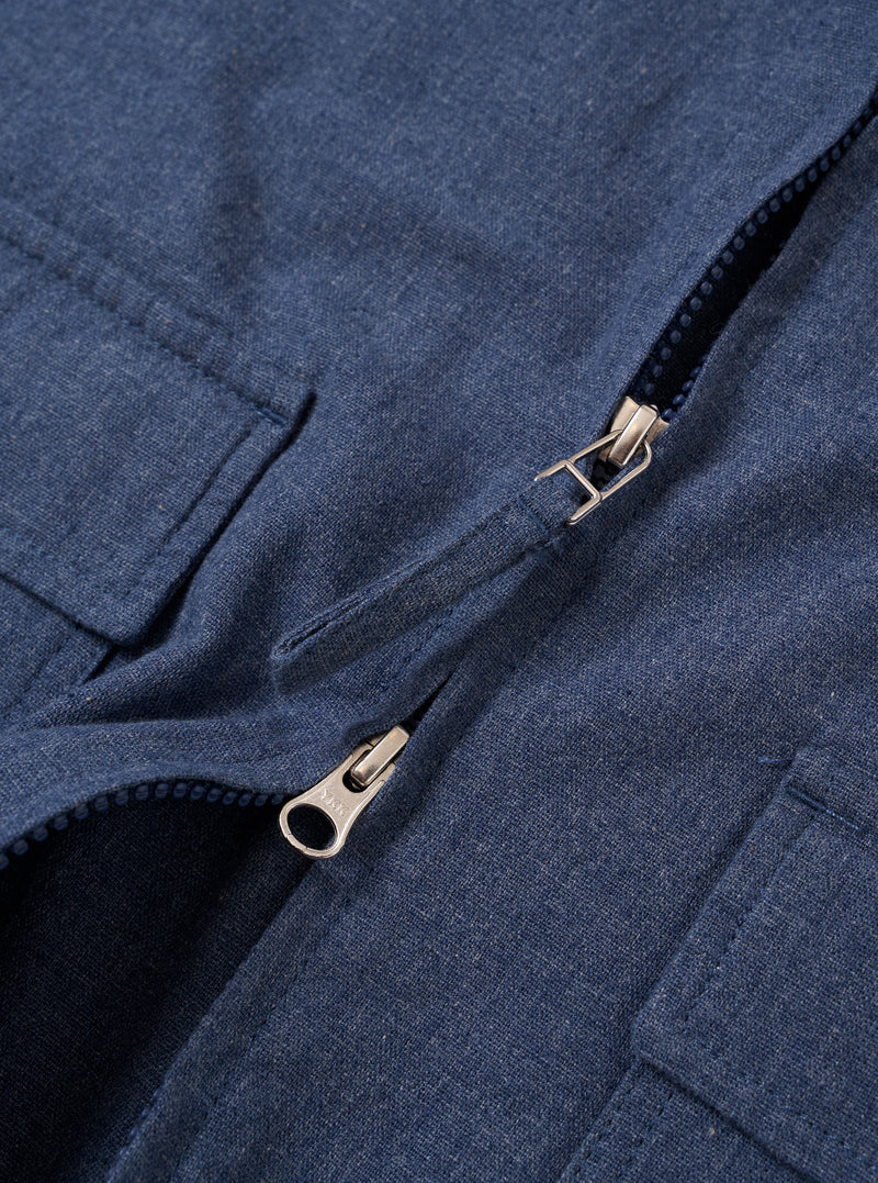 The Blue Sintra Recycled Cotton E130 Jacket is shown from the back as a flat lay against a plain white background. The image highlights the jacket's relaxed, boxy fit, tonal elbow patches for reinforcement, and adjustable hem tabs with button closures. The blue fabric has a slightly slubby, textured appearance.