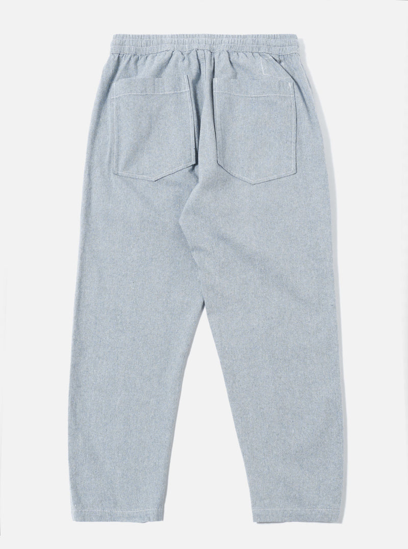 The Light Indigo Jean Cloth Reworked Hi Water Trouser is shown from the back as a flat lay against a plain white background. The image highlights the two rear patch pockets and the elasticated waistband of the light blue organic cotton trousers. The cropped, slim-fit design is visible with clean stitching details along the seams and hem.