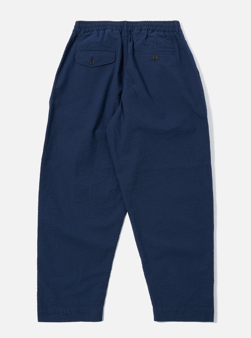 The Navy Derby Stripe Oxford Pant is shown from the back as a flat lay against a plain white background. The image highlights the two rear patch pockets, an elasticated waistband with a drawstring, and a subtle vertical stripe pattern on the navy cotton fabric.
