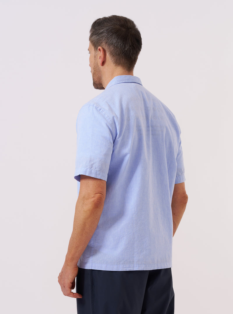 A model wears the Sky Blue Sido Linen Mix Road Shirt, shown from the back against a plain white background. The shirt features a relaxed fit, a straight hem, and a simple back yoke. The sky blue fabric has a visible linen-blend texture with a subtle, multi-tonal weave. No mannequin is present in the image.