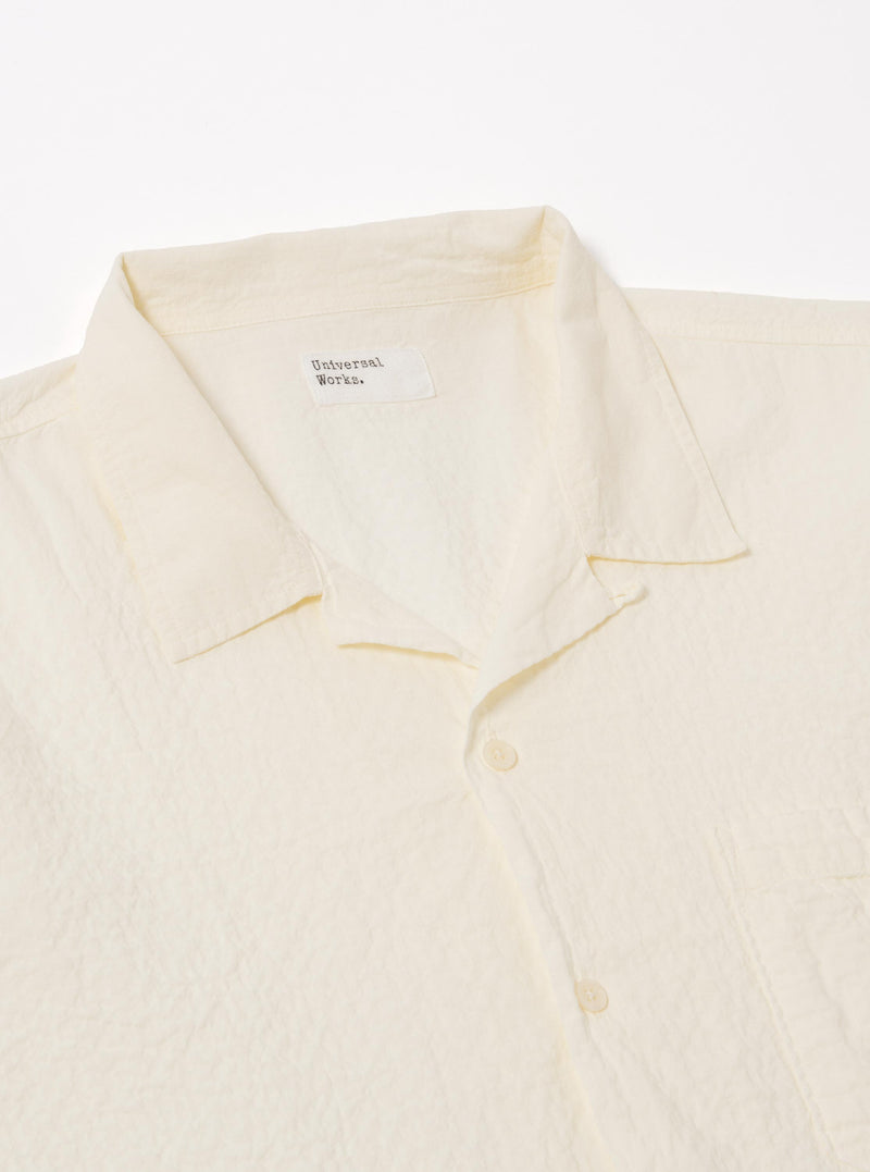 The Ecru Arten Seersucker Road Shirt is shown from the back as a flat lay against a plain white background. The image highlights the shirt's straight hem, short sleeves, and the distinct puckered texture of the ecru seersucker fabric.