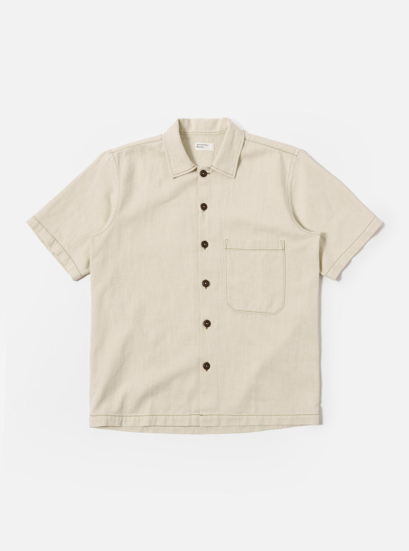 The Ecru Koko Cotlin S/S Fatigue Shirt is shown as a flat lay against a white background. The shirt features a button-down front, a classic collar, and two large patch pockets on the chest. The short-sleeved garment is made from a textured ecru-colored cotton-linen blend fabric.