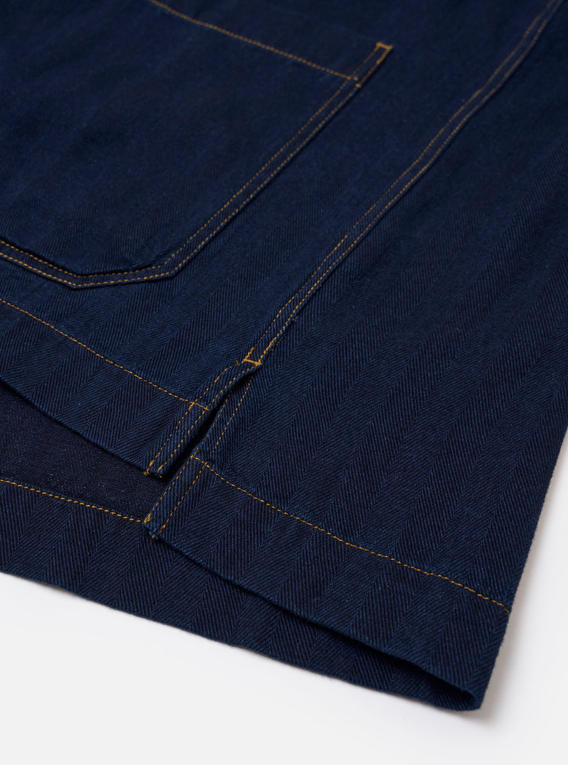 The Indigo Recycled Herringbone Smock Overshirt is shown from the back as a flat lay against a plain white background. The image highlights the straight hem, which is slightly longer than the front, and the textured herringbone weave of the indigo-colored fabric.