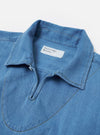 The Washed Indigo Recycled Herringbone Smock Overshirt is shown from the back as a flat lay against a plain white background. The image highlights the horizontal yoke across the shoulders and the clean, straight hem of the garment. The washed indigo blue fabric features a visible herringbone weave texture throughout.