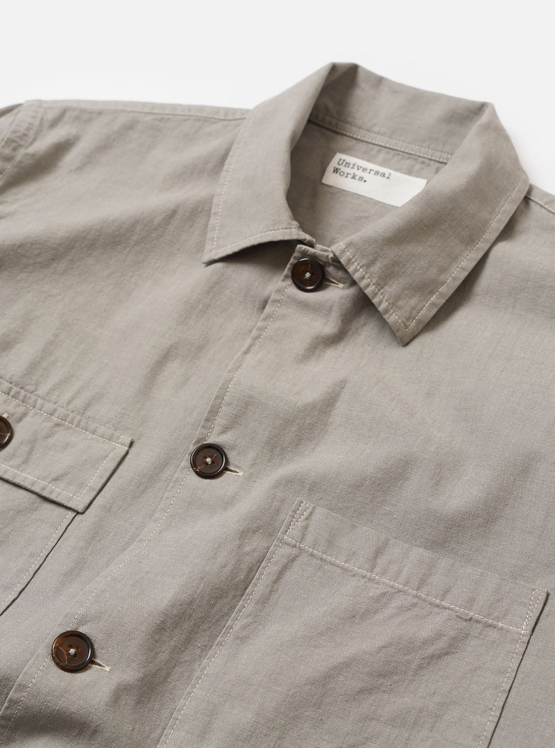 The Grey Izumi Cotton Dockside is shown from the back as a flat lay against a plain white background. The garment features a straight hem, a simple yoke across the shoulders, and a relaxed fit. The fabric has a subtle textured appearance in a solid grey color.