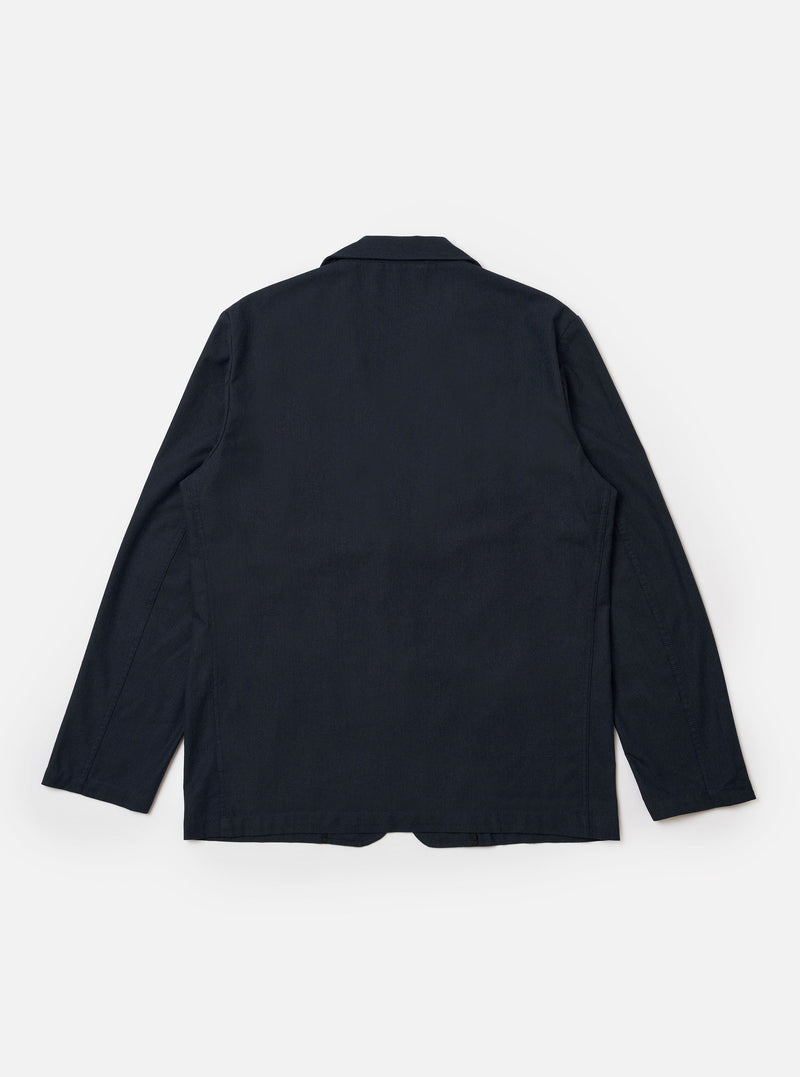 The Navy Valencia Cotton Two Button Jacket is shown from the back as a flat lay against a plain white background. The image highlights the jacket's clean construction, featuring a central vertical seam and a single vent at the hem. The navy blue cotton fabric has a smooth, matte finish.