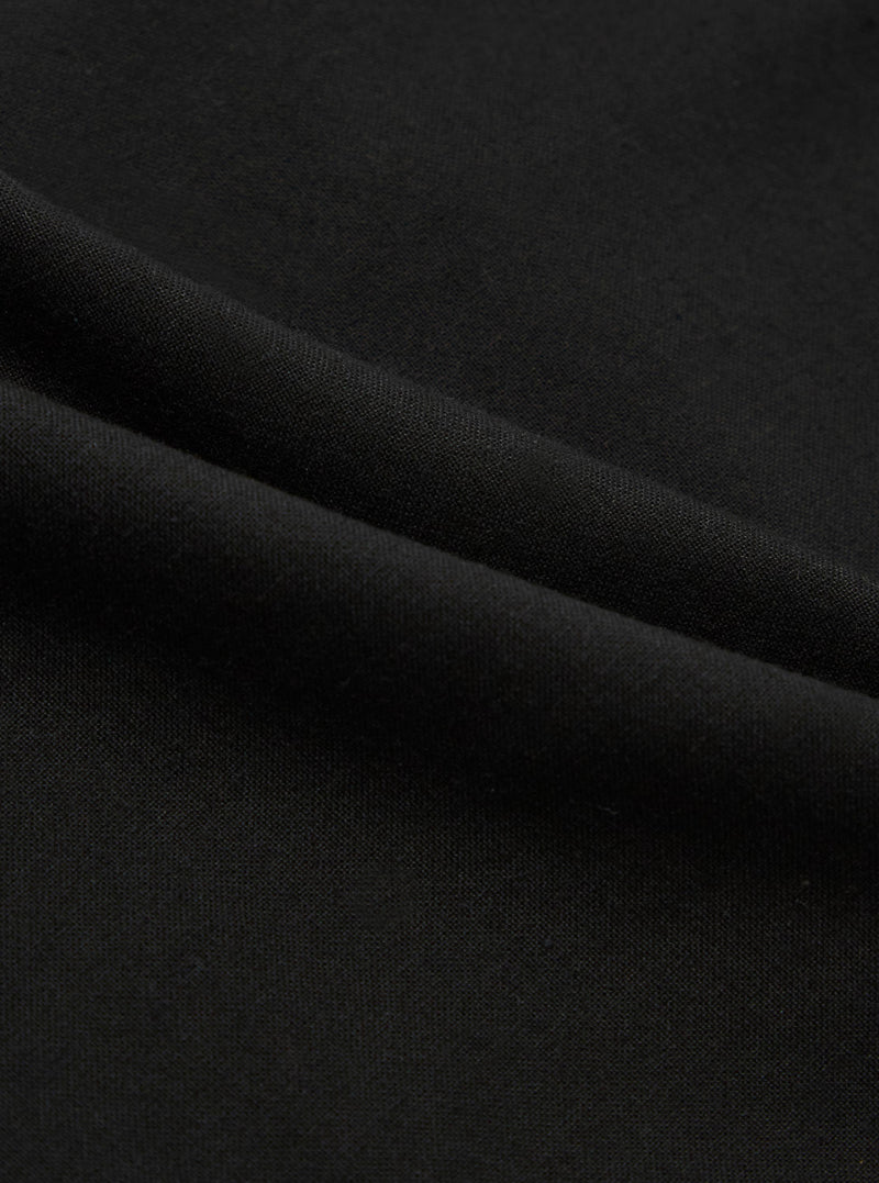 A close-up fabric swatch of the Black Valencia Cotton Military Chino displays the solid black color and the fine, woven texture of the Valencia cotton blend. The material fills the entire frame, providing a detailed view of the fabric's surface.