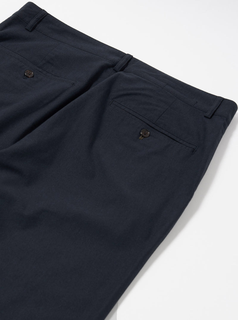 The Navy Valencia Cotton Military Chino is shown from a rear angle as a flat lay against a plain white background. The image highlights the two rear patch pockets, one with a button-down flap, and the clean stitching along the waistband and central seam. The dark navy fabric has a visible textured quality.