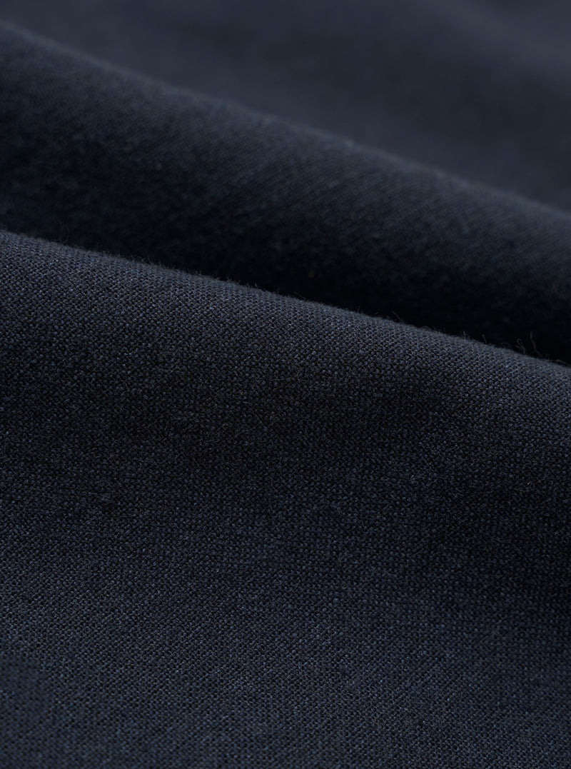 A close-up swatch image of the Navy Valencia Cotton Pleated Track Pant fabric. The image focuses on the textile detail, showing a deep navy blue color with a fine, clean, plain weave texture.