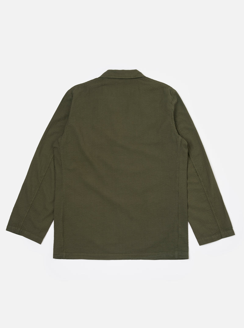 The Olive Merida Seersucker Three Button Jacket is shown as a flat lay against a white background. The jacket features a three-button front closure, a notched lapel, two large lower patch pockets, and one chest patch pocket. The olive green fabric has a distinct puckered seersucker texture throughout.