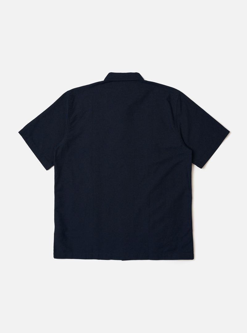The Navy Classic Oxford Tropicana Shirt is shown from the back as a flat lay against a white background. The image highlights the relaxed fit, one-piece collar, and short, loose sleeves. The hem is slightly curved and longer at the back with small side splits.