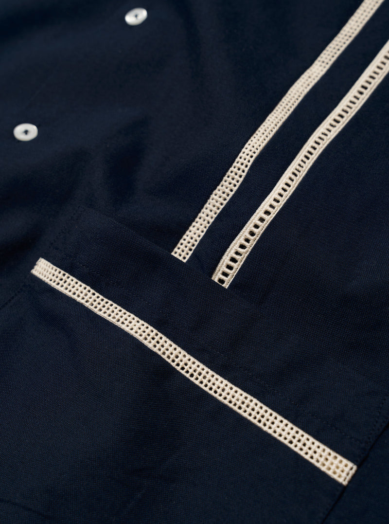 The Navy Classic Oxford Tropicana Shirt is shown from the back as a flat lay against a white background. The image highlights the one-piece collar, a straight back yoke, and a side split hem that is longer at the back. The navy blue Oxford cotton fabric has a visible textured weave.