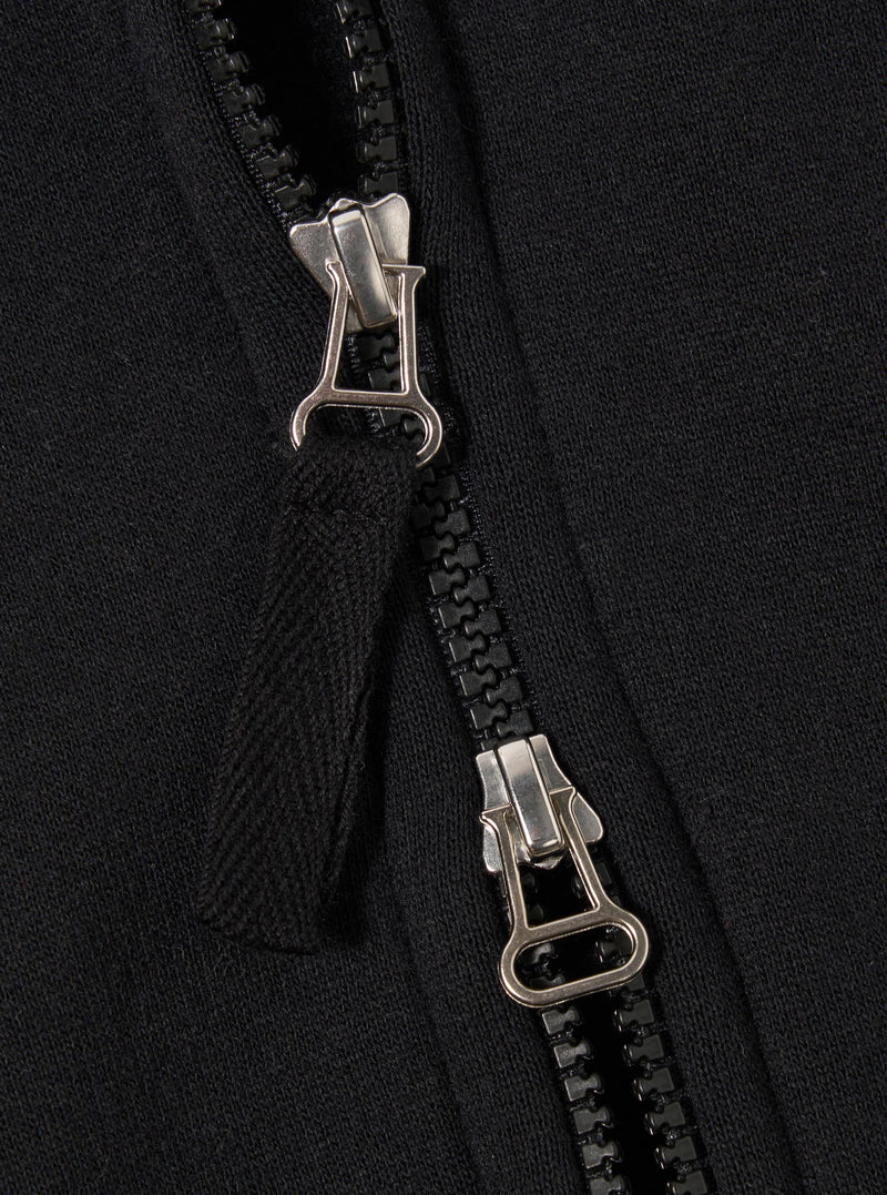 The Black Recycled Cotton Blend Jersey Tyler Jacket is shown in a detail view as a flat lay against a white background. The image highlights the jacket's textured black jersey fabric, a ribbed hem, and a single front patch pocket with a velcro fastening.
