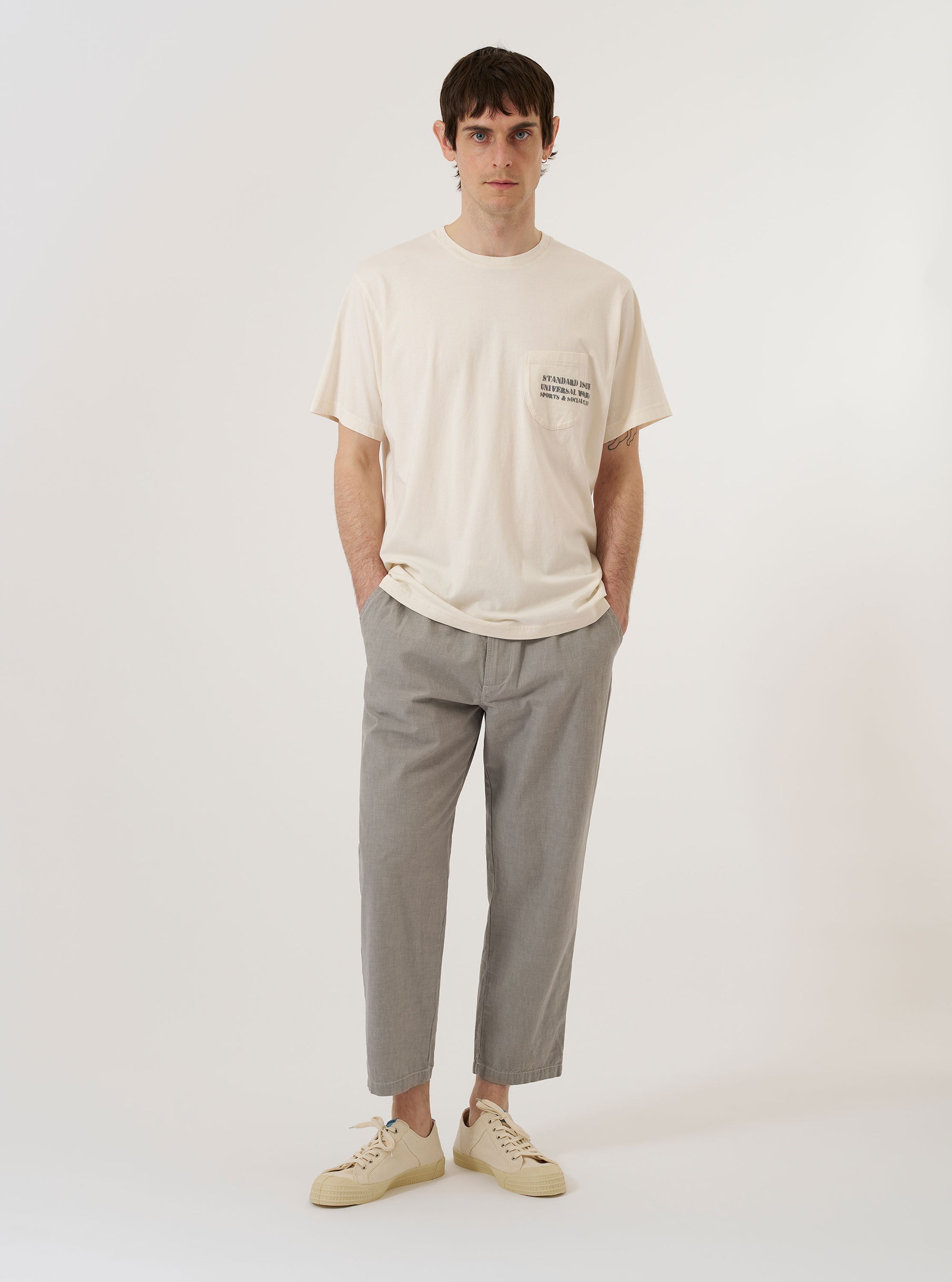 The Ecru Organic Jersey Print Pocket Tee is shown as a flat lay against a white background. The short-sleeve t-shirt is an off-white ecru color and features a crew neck and a single chest pocket on the left side with a graphic print detail.