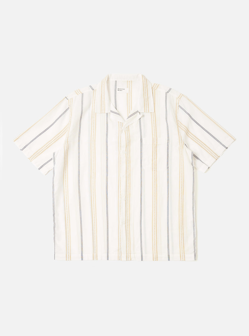 The Ecru/Navy/Sand Hendrix Stripe Road Shirt is shown as a flat lay against a plain white background. The shirt features a vertical stripe pattern in ecru, navy, and sand, a relaxed camp collar, and a central button-down front. It has short sleeves and a single patch pocket on the left chest.