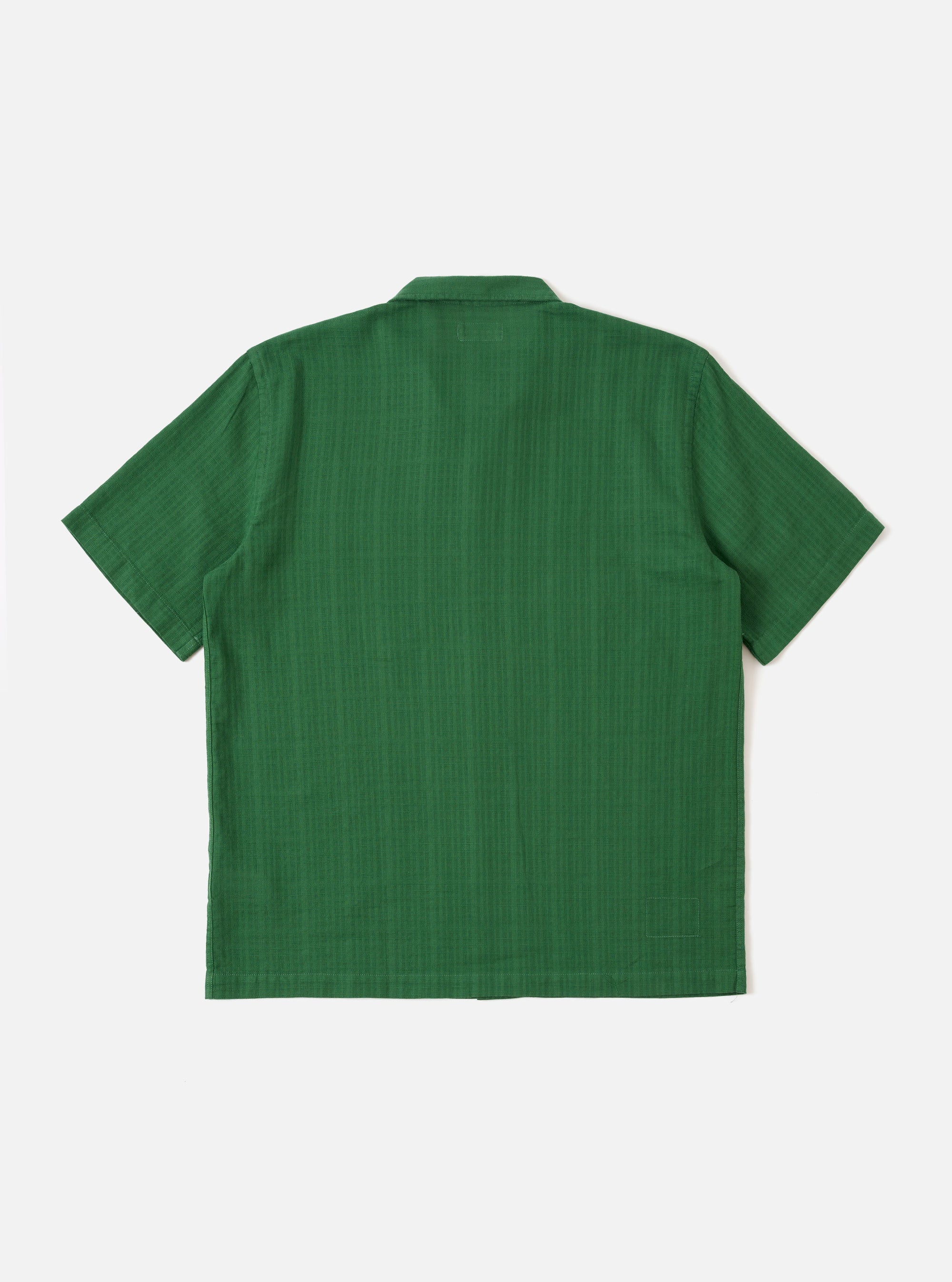 The Green Letts Cotton Road Shirt is shown from the back as a flat lay against a plain white background. The image highlights the short sleeves, a straight hem, and the clean construction of the back panel, showcasing the textured green Letts cotton fabric.