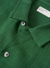 The Green Letts Cotton Road Shirt is shown from the back as a flat lay against a plain white background. The image highlights the straight hem and the clean, simple construction of the shirt's rear panel. The green cotton fabric features a visible textured weave.