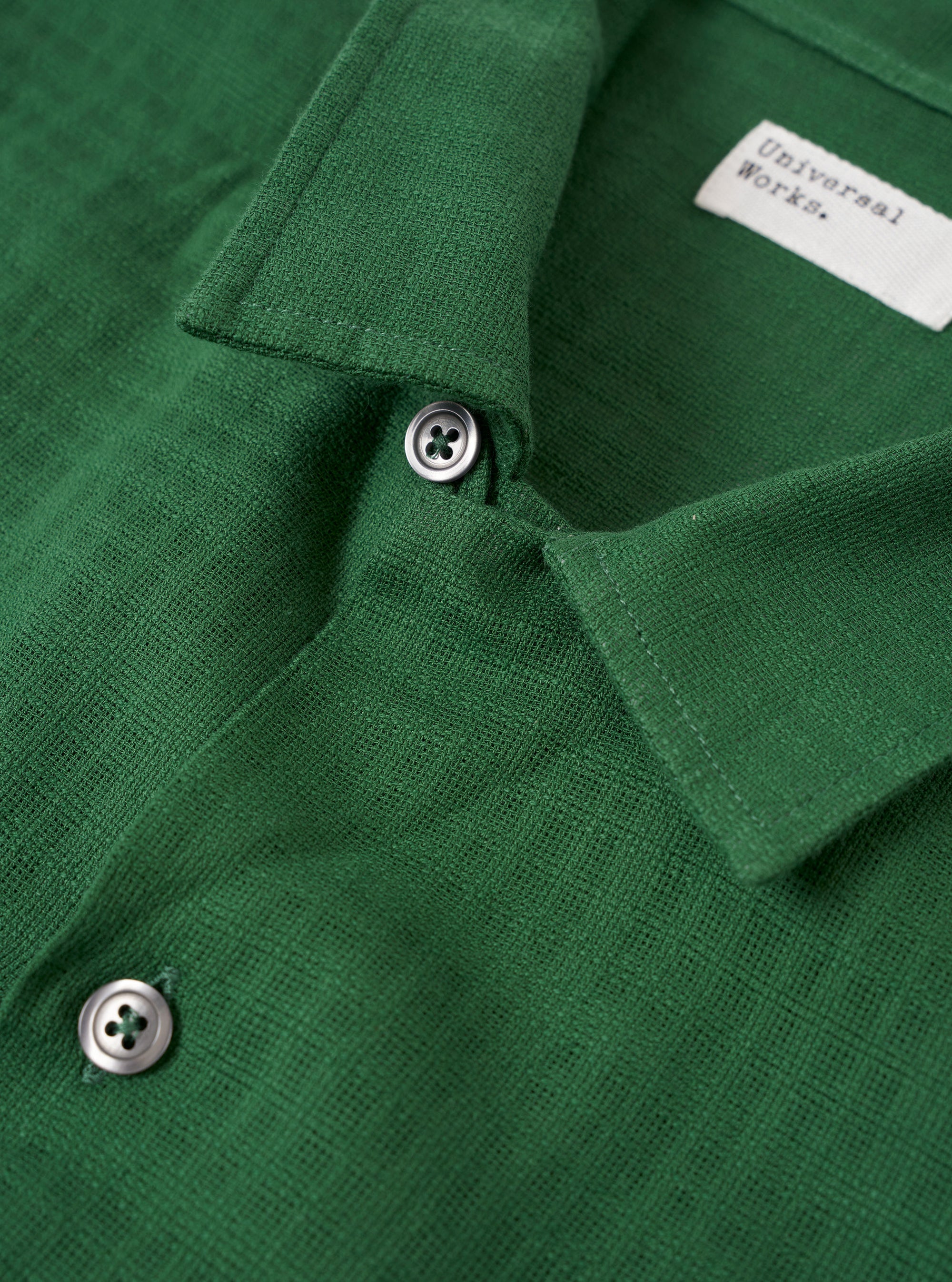 The Green Letts Cotton Road Shirt is shown from the back as a flat lay against a plain white background. The image highlights the straight hem and the clean, simple construction of the shirt's rear panel. The green cotton fabric features a visible textured weave.