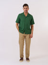 The Green Letts Cotton Road Shirt is shown as a flat lay against a white background. The shirt features a camp collar, a central button-down front, and two large patch pockets at the waist. The short-sleeved garment is made from a green cotton fabric.