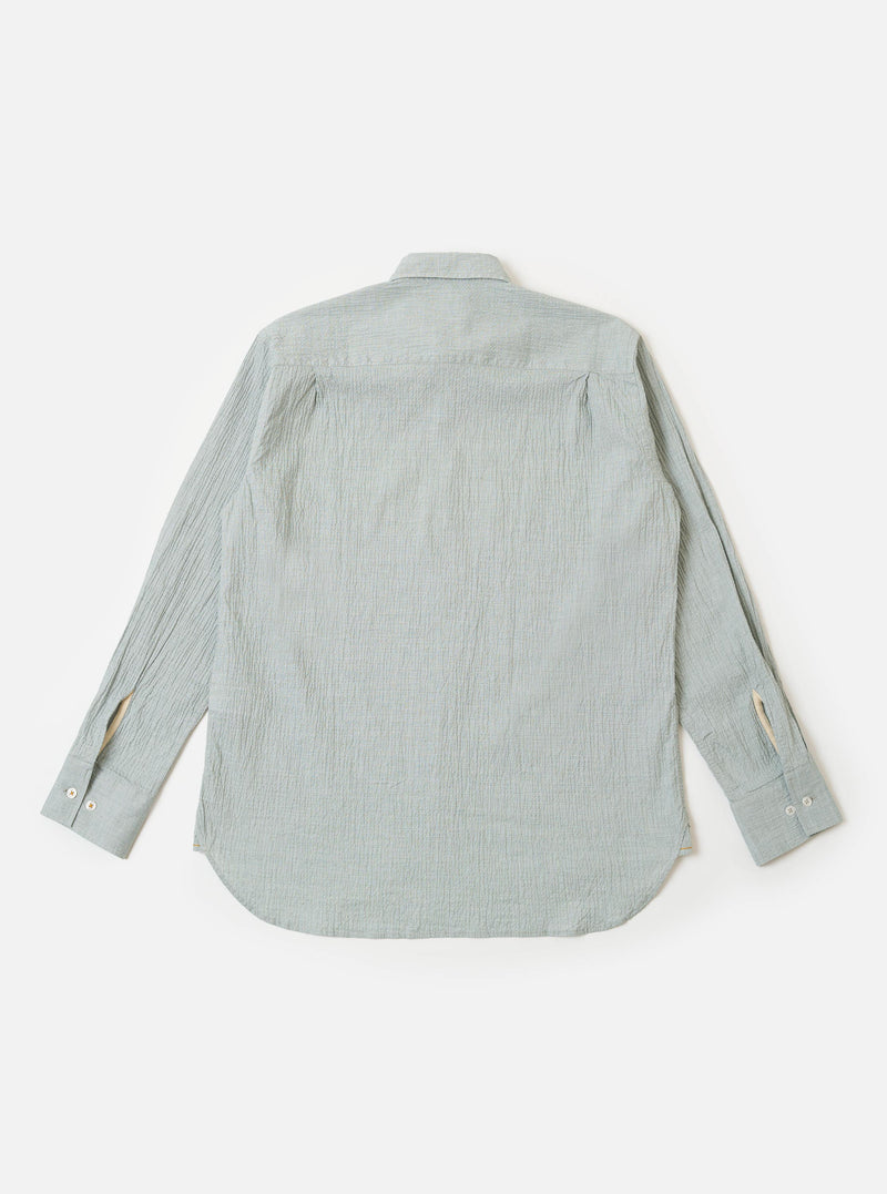 The Green Seersucker Square Pocket Shirt is shown from the back as a flat lay against a plain white background. The image highlights the shirt's textured green seersucker fabric, a straight hem, and a simple one-piece back panel with a central box pleat.