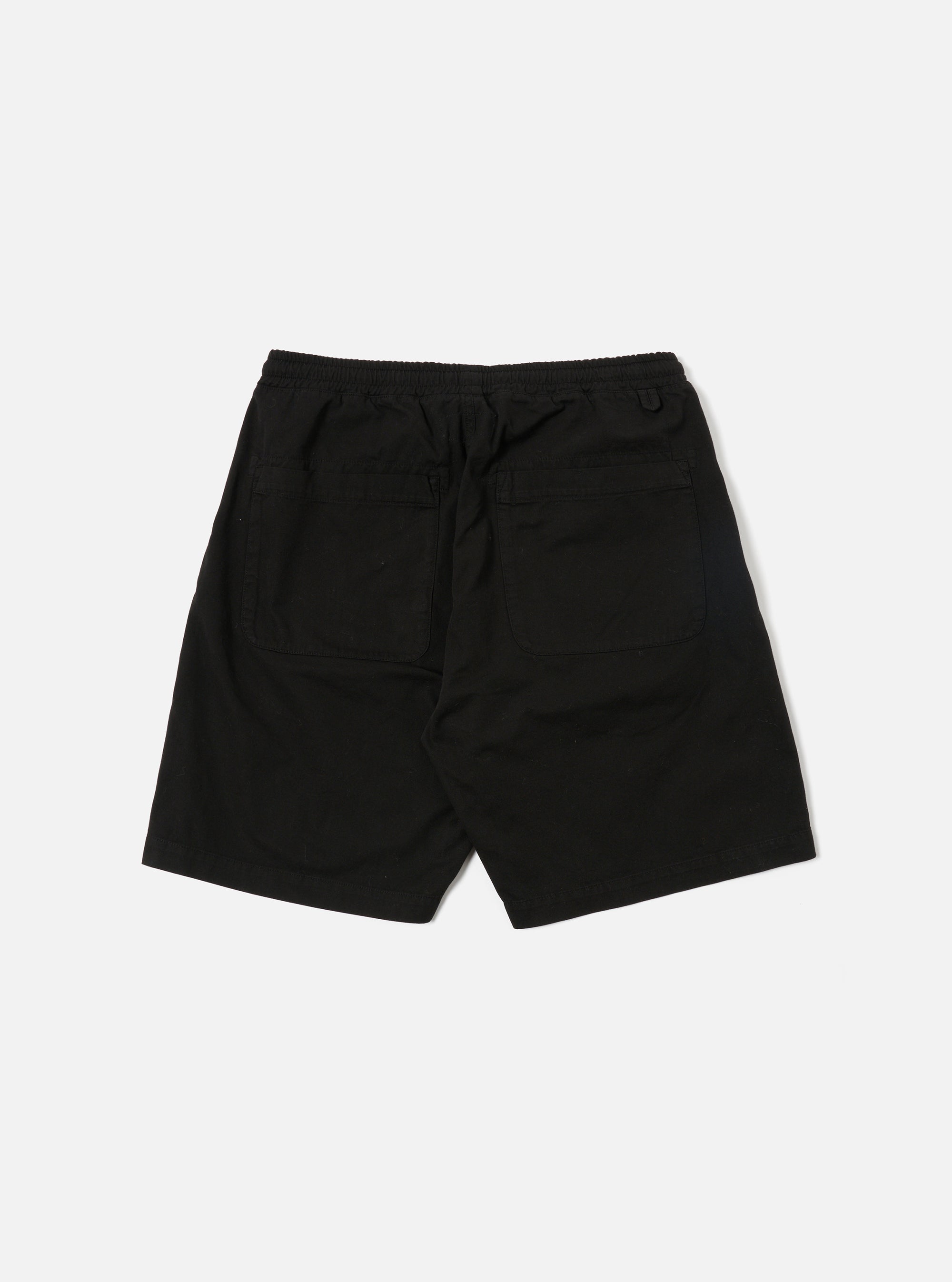 A model wears the Black Kelly Cotton Simple Short, which are shown from a front angle against a plain white background. The shorts feature an elasticated waistband with an adjustable drawstring and vertical side pockets. The fabric has a fine ribbed texture, and the garment is cut to sit just above the knee. No other accessories or clothing items are prominent in the focus of this image.
