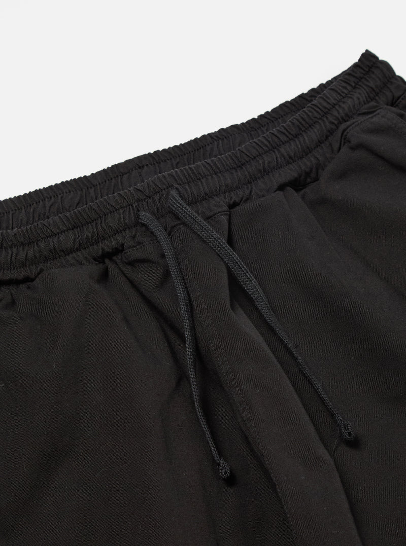 The Black Kelly Cotton Simple Short is shown from the back as a flat lay against a plain white background. The shorts feature an elasticated waistband and a single patch pocket on the right rear side. The fabric is a solid black cotton with visible stitching details.