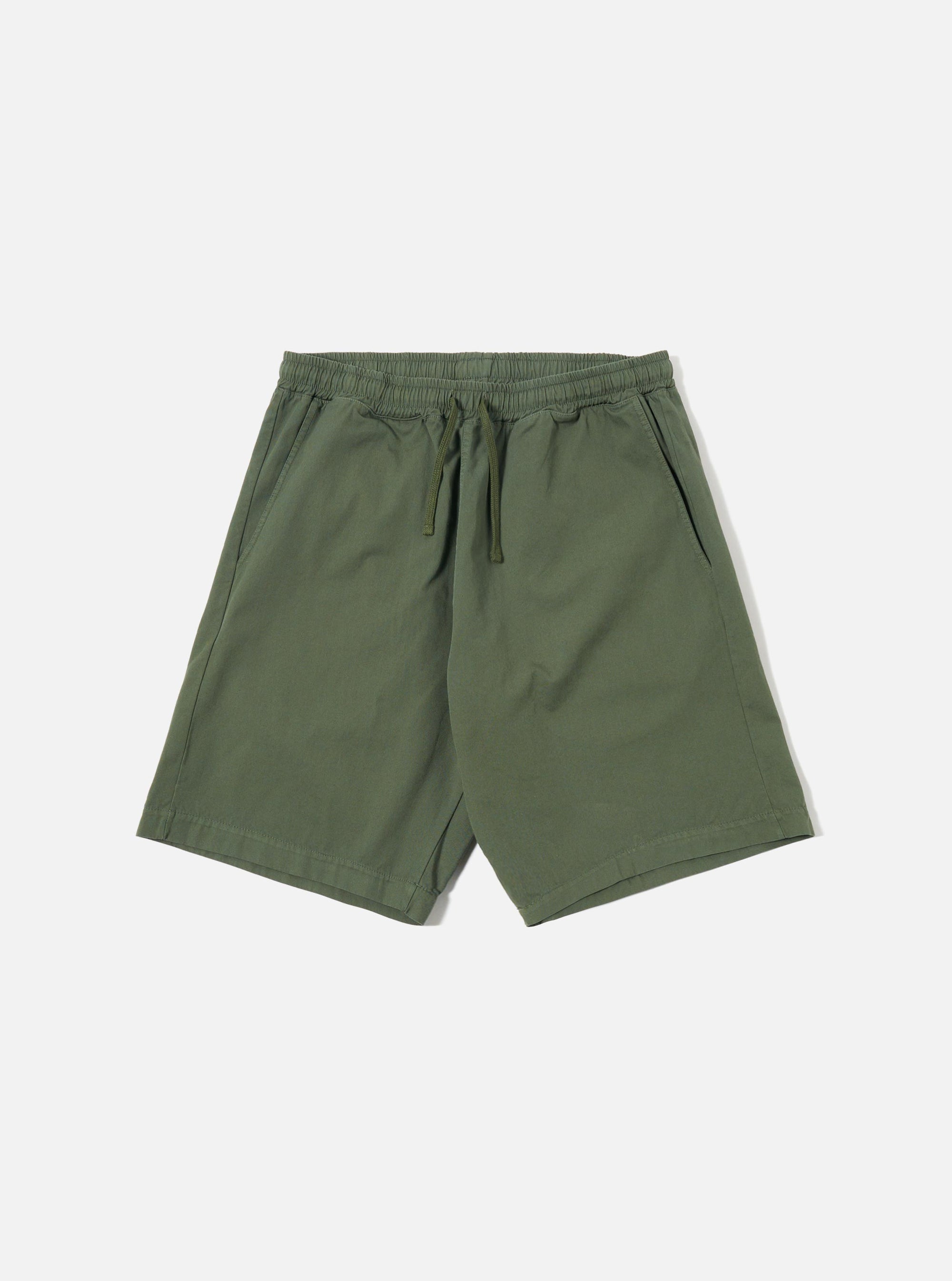 The Olive Kelly Cotton Simple Short is shown as a flat lay against a plain white background. The shorts feature an elasticated waistband with a matching olive green drawstring and two side pockets. The fabric is a solid olive green cotton with a smooth, matte finish.