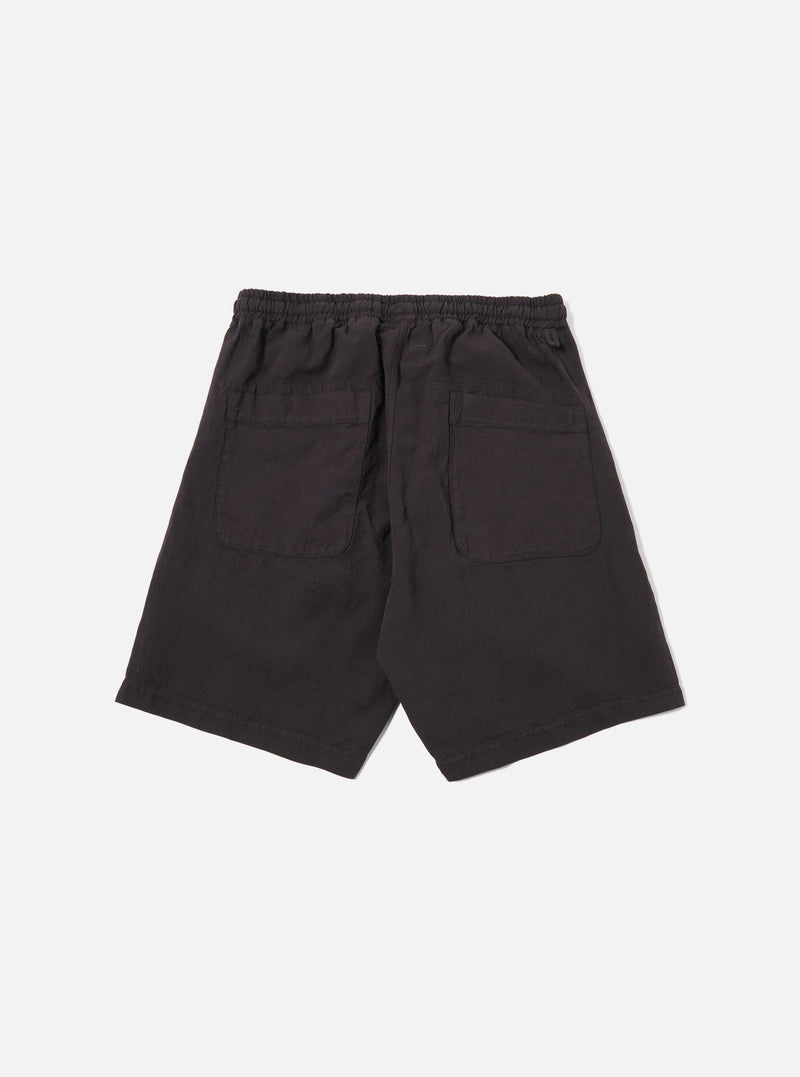 The Licorice Lyo Linen Mix Simple Short is shown as a flat lay against a white background. These brown shorts feature an elasticated waistband with an adjustable drawstring, side angled pockets, and a relaxed, wide-leg fit. The fabric has a visible textured weave characteristic of a linen-lyocell blend.