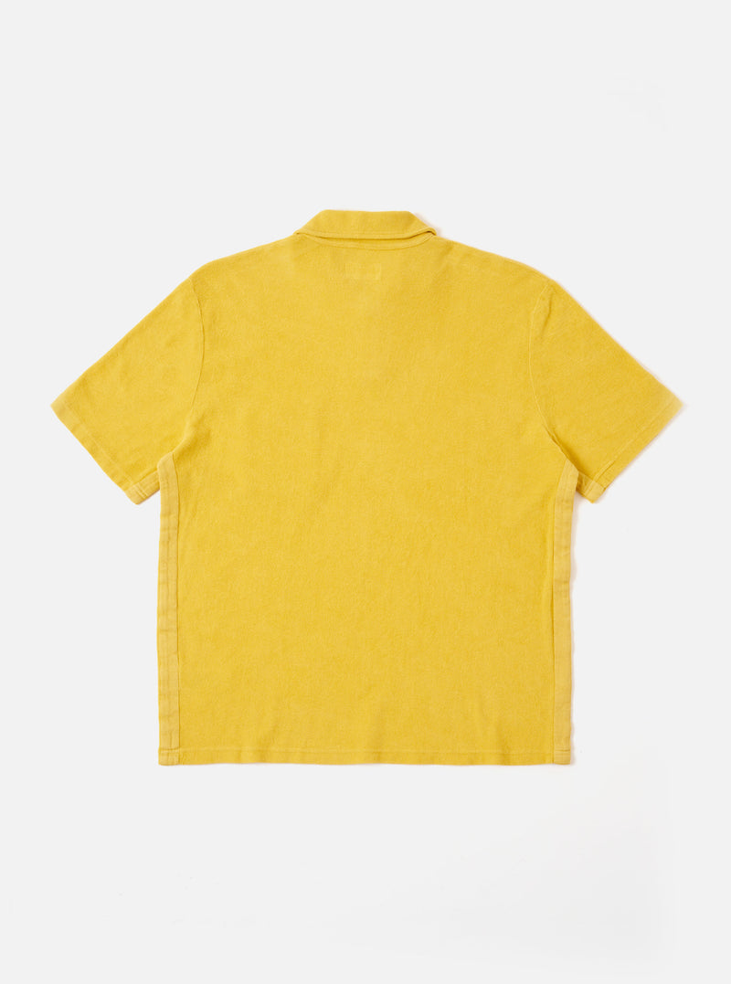 The Yellow Light Weight Terry Newlyn Polo is shown from the back as a flat lay against a plain white background. The image highlights the soft, looped texture of the yellow terry fabric, the short sleeves, and the straight hem.