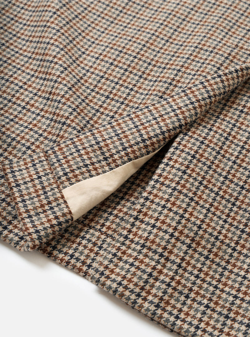 Rear view of the Taupe Lester Dogtooth Stan Coat displayed against a plain off-white studio background. The shot focuses on the clean back tailoring, single center vent, and intricate taupe check pattern.