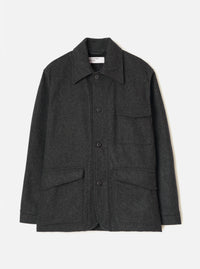 Grey marl wool chore jacket laid flat on a light grey seamless backdrop. Point collar with a Universal Works woven label at the neck. Four button front placket with dark buttons. Two chest patch pockets and two large flap pockets at the hem. Long sleeves with plain cuffs. Brushed, lightly flecked wool fabric throughout.