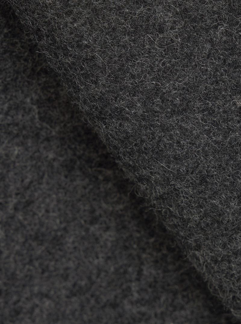 Close-up fabric detail of the grey marl Mowbray Heavy Duty Jacket, showing a densely textured wool-blend surface with tightly coiled fibres and a mix of charcoal and light grey tones. The shot highlights the fabric's thick, tactile pile with soft folds creating depth and shadow.