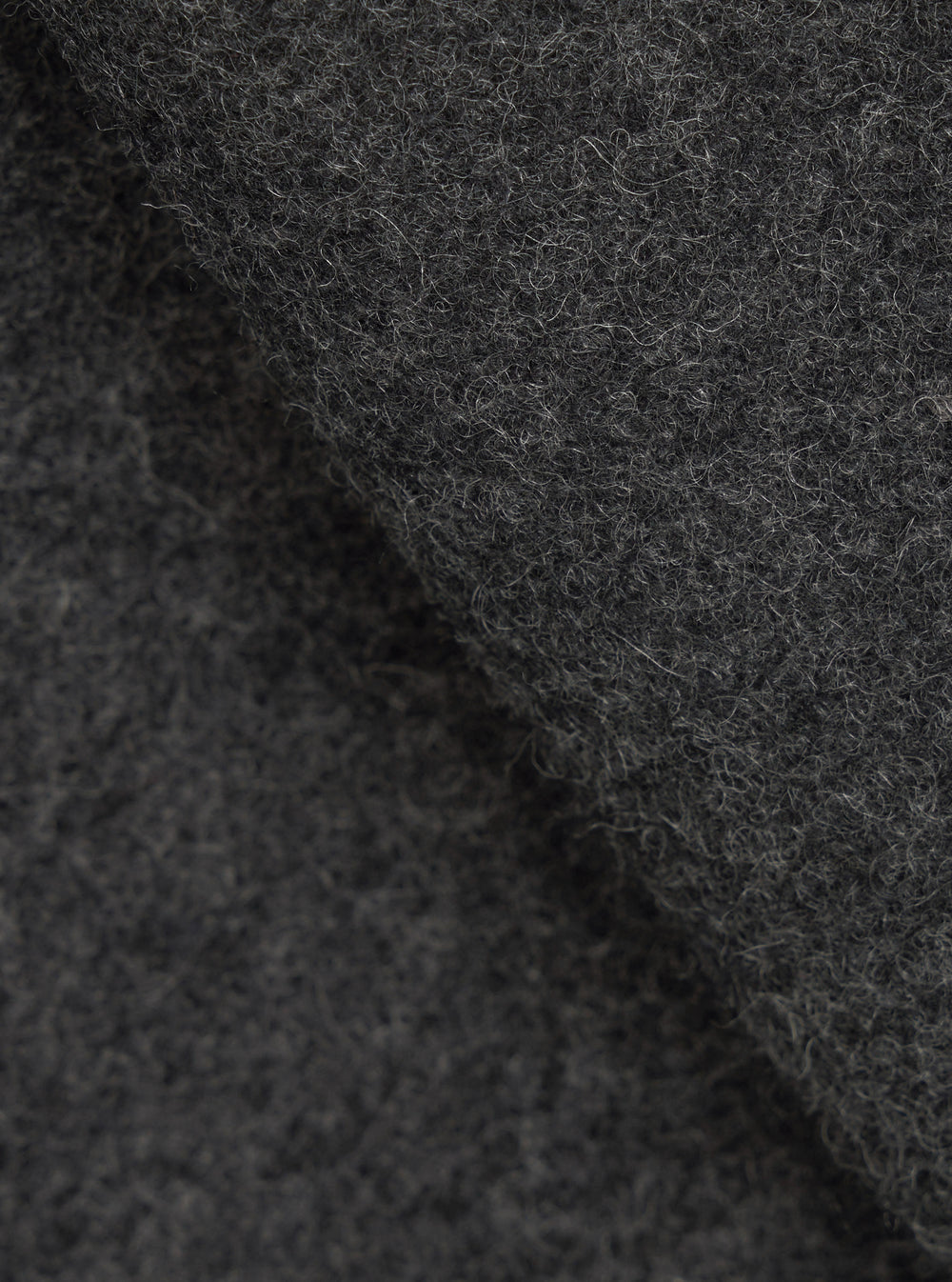 Close-up fabric detail of the grey marl Mowbray Heavy Duty Jacket, showing a densely textured wool-blend surface with tightly coiled fibres and a mix of charcoal and light grey tones. The shot highlights the fabric's thick, tactile pile with soft folds creating depth and shadow.