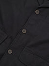 Close-up flat lay of the black brushed moleskin Franck jacket, showing the single-breasted button placket with three four-hole dark horn-effect buttons on a loophole fastening. Two patch pockets are visible at the lower chest and hip. The soft, dense fabric texture is prominent throughout. White studio background.