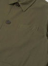 Close-up detail of the olive brushed moleskin Franck jacket on a plain white studio backdrop. The point collar, dark horn button at the neck, and a second button on the left chest placket are visible. A welt chest pocket with bartack stitching sits on the front body. The fabric has a smooth, dense texture.