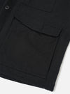 Close-up detail of a black brushed moleskin gilet, shot flat on a white surface. The image focuses on the front left section, showing a large flap patch pocket with topstitching and a smaller chest pocket above it. A single dark button is visible on the placket. The dense, matte fabric texture is clearly visible.