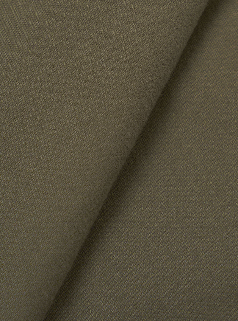 Close-up of olive brushed moleskin fabric folded diagonally, showing a fine, dense weave with a soft matte surface texture. The plain-coloured cloth has a subtle nap visible across both layers. No garment construction details are shown.