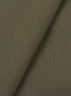 Close-up of olive brushed moleskin fabric folded diagonally, showing a fine, dense weave with a soft matte surface texture. The plain-coloured cloth has a subtle nap visible across both layers. No garment construction details are shown.