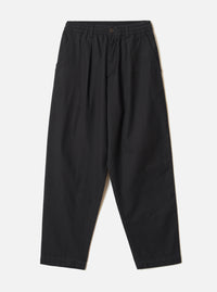 Black brushed moleskin pleated track pants laid flat on a light grey seamless backdrop. The elasticated waistband features a single dark button at the centre front. Slant side pockets sit at the hips. The wide-leg silhouette tapers slightly toward the plain, unfinished hem. Fabric has a soft, matte texture throughout.