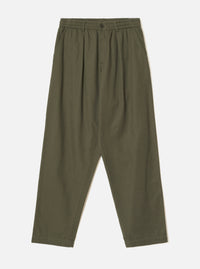 Olive brushed moleskin pleated track pants laid flat on a plain light grey studio backdrop. The elasticated waistband features a single dark button at the centre front. Pleats run from waist to thigh on each leg, with slanted side pockets. The wide leg tapers slightly toward the cropped hem.