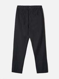 Black brushed moleskin military chinos laid flat on a light grey studio backdrop. The waistband features belt loops and a single dark button fastening at the centre front. Slant side pockets sit at the hips. The fabric has a subtle brushed texture. The trousers taper slightly from a relaxed thigh to a narrower ankle hem.