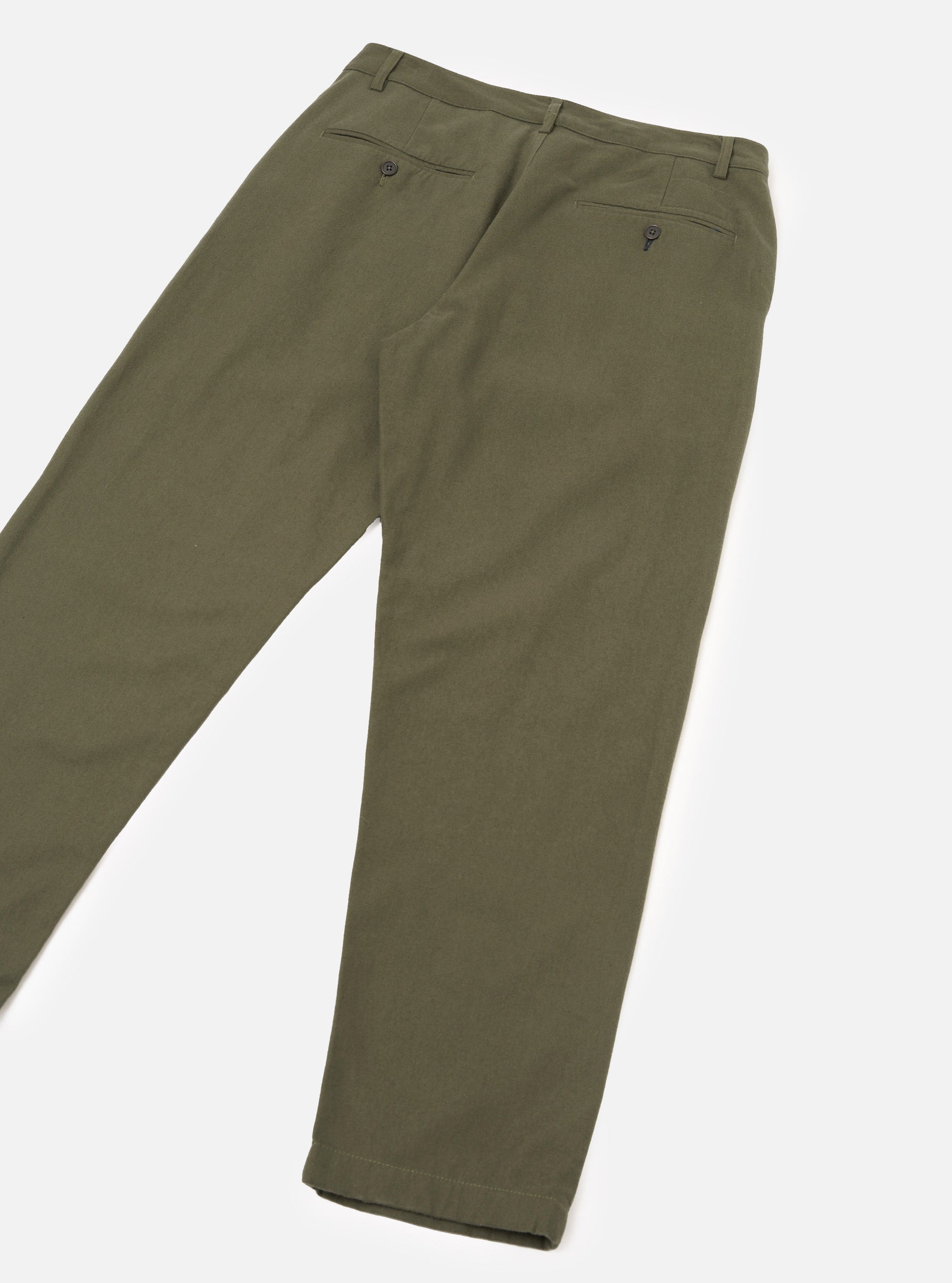Olive brushed moleskin military chinos laid flat on a white studio surface, reverse side showing. Two button-fastened welt back pockets are visible, along with a waistband with belt loops. The fabric has a soft, fine-napped texture. Legs taper to a plain hemline.