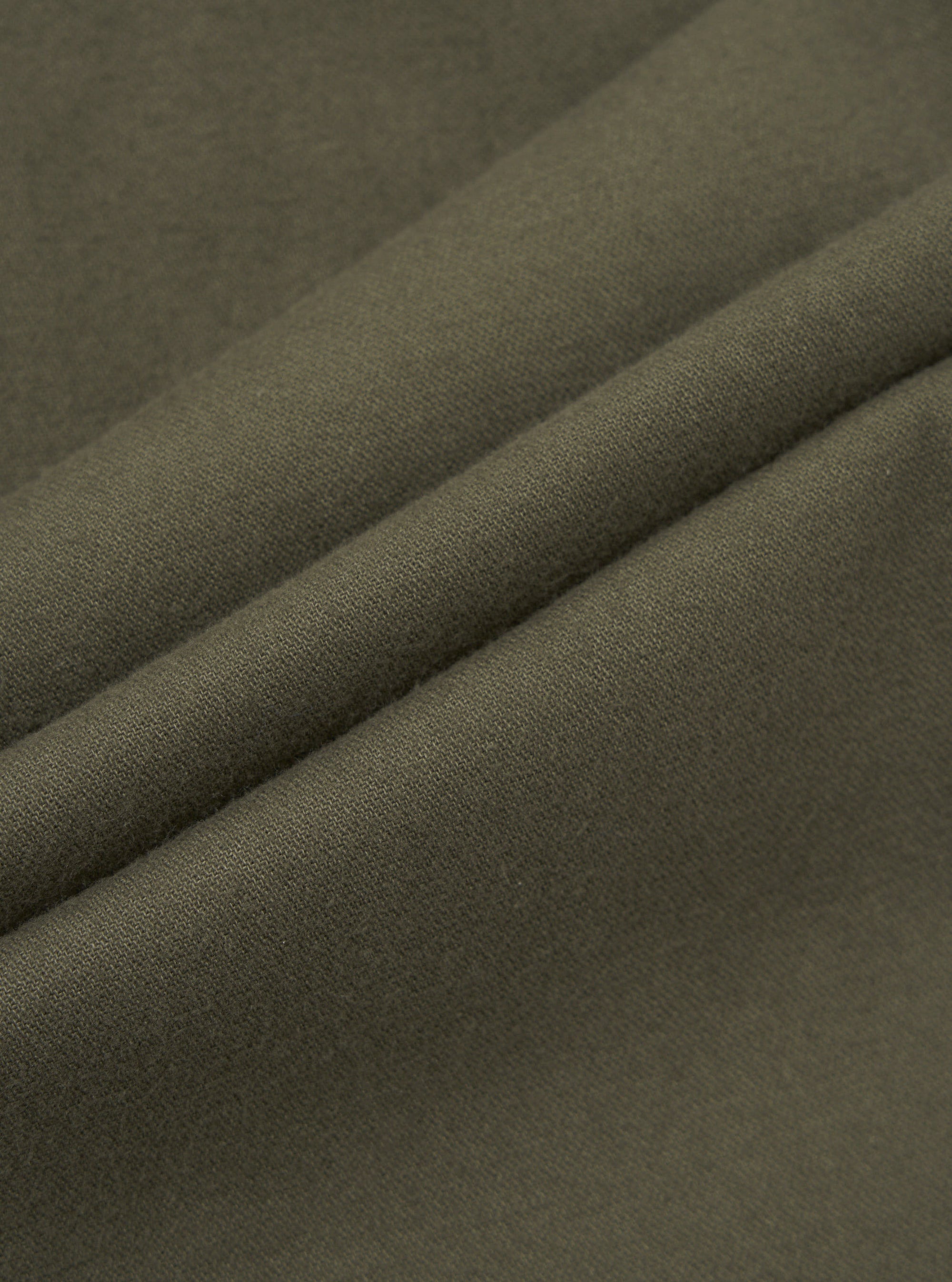 Close-up of olive brushed moleskin fabric, showing a soft, fine-textured surface with a subtle matte finish. The cloth is folded to reveal two raised ridges, highlighting the fabric weight and smooth hand-feel. The solid khaki-green tone is consistent throughout, with no pattern or sheen visible.