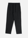 Black brushed moleskin hi water trousers laid flat on a plain light grey studio backdrop. The elasticated waistband features a dark drawcord and a single dark button at the centre front. Slanted side pockets sit at the hips. The relaxed leg tapers to a cropped, unfinished hem. Fabric has a soft, brushed texture throughout.