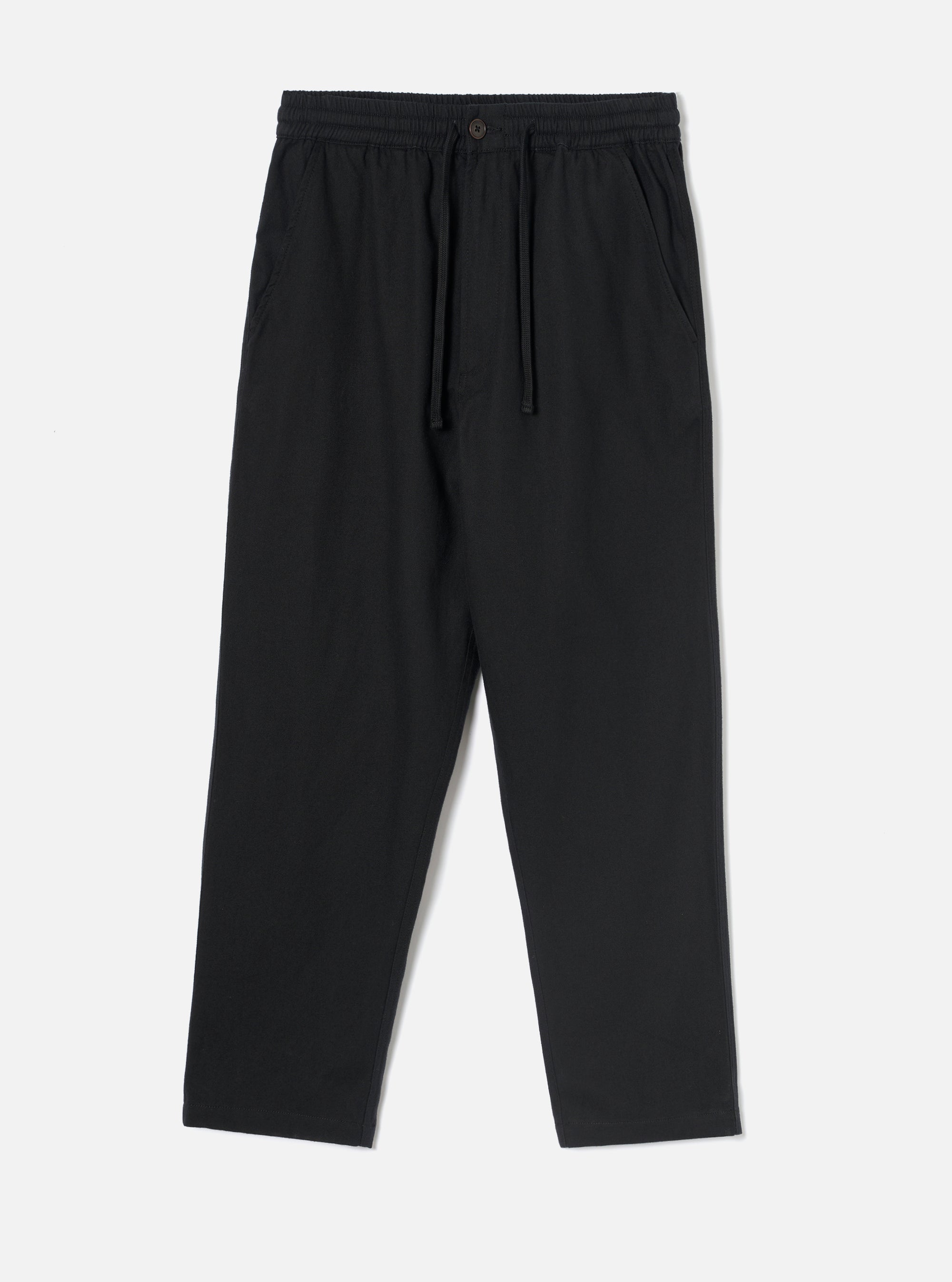 Black brushed moleskin hi water trousers laid flat on a plain light grey studio backdrop. The elasticated waistband features a dark drawcord and a single dark button at the centre front. Slanted side pockets sit at the hips. The relaxed leg tapers to a cropped, unfinished hem. Fabric has a soft, brushed texture throughout.