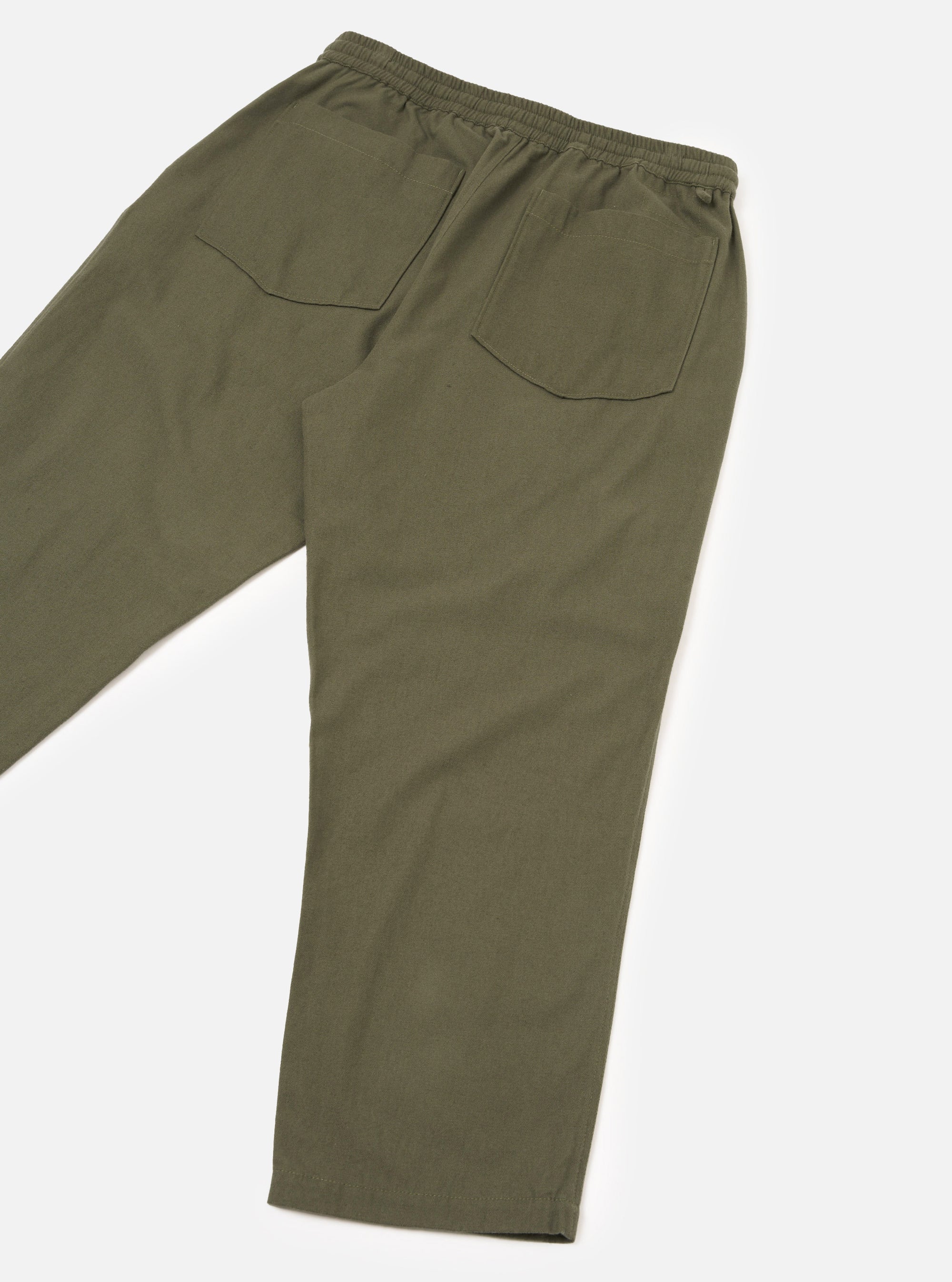 Flat lay of olive brushed moleskin hi-water trousers on a white studio backdrop, shot from the rear at an angle. The elasticated waistband is visible at the top, with two large patch pockets on the back. The plain, lightly textured fabric has a soft matte finish. The cropped leg hem is visible at the bottom.