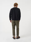 A back view of a model wearing the Universal Works Olive Brushed Moleskin Hi Water Trouser against a plain studio background. The photo highlights the high-water cropped hem, olive brushed cotton fabric, and rear patch pocket details.